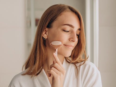 Woman using a gua sha roller on her face