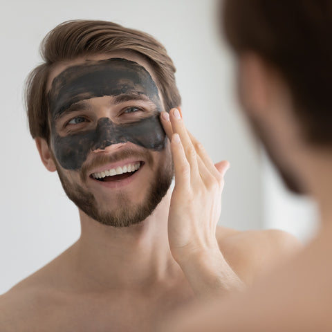 man applying charcoal face mask