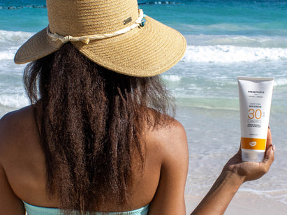 Woman on the beach holding Green People sun cream